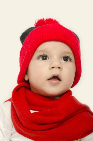 Bebé inocente usando un sombrero rojo y un silenciador y luciendo adorable. Un niño pequeño vestido para el invierno. Recién nacido mirando a su madre y sonriendo — Foto de Stock