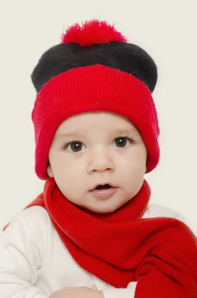 Bebé inocente usando un sombrero rojo y un silenciador y luciendo adorable. Niño pequeño vestido para el invierno —  Fotos de Stock