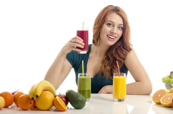 Happy woman having a table full of organic food,juices and smoothie. Cheerful young woman eating healthy salad and fruits. Isolated on white. — Stock Photo, Image