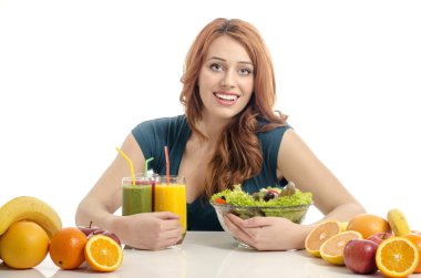 Organik gıda, meyve suları ve güler yüzlü dolu bir tablo sahip mutlu bir kadın. yeme sağlıklı salata ve meyve neşeli genç bir kadın. beyaz izole