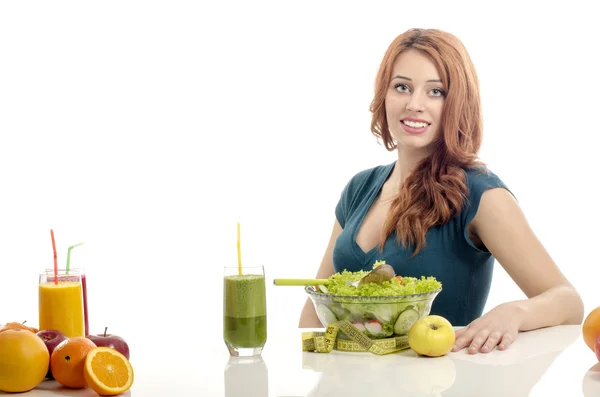 Donna felice avere un tavolo pieno di cibo biologico, succhi di frutta e frullato. Giovane donna allegra mangiare insalata sana e frutta. Isolato su bianco — Foto Stock