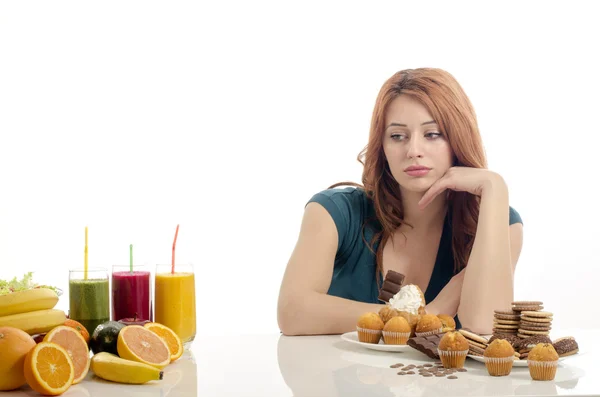 Mulher escolher entre frutas, smoothie e alimentos orgânicos saudáveis contra doces, açúcar, lotes de doces, alimentos não saudáveis. Tratando seu vício em doces com frutas e vegetais — Fotografia de Stock