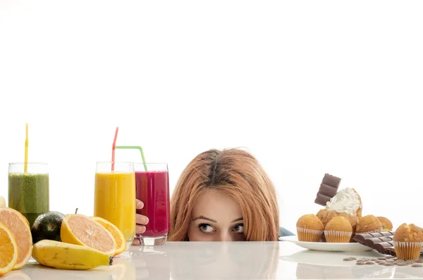 Mujer eligiendo entre frutas, batidos y alimentos orgánicos saludables contra dulces, azúcar, muchos dulces, alimentos poco saludables. Tratamiento de la adicción a los dulces con frutas y verduras —  Fotos de Stock