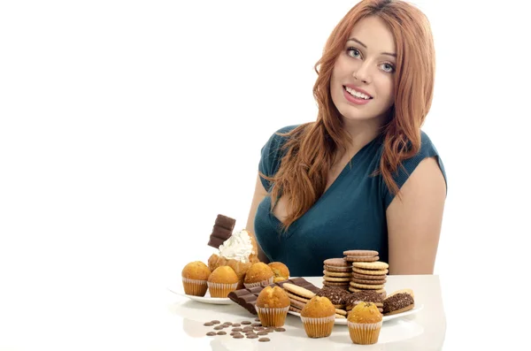 Mädchen haben Spaß und essen viele Kekse, Muffins, Fondants. Frau liebt Süßigkeiten, Bonbons, Schokolade und Zucker — Stockfoto