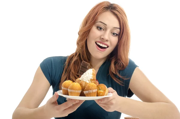 Mädchen haben Spaß und essen viele Kekse, Muffins, Fondants. Frau liebt Süßigkeiten, Bonbons, Schokolade und Zucker — Stockfoto