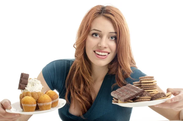 Chica divirtiéndose y comiendo un montón de galletas, magdalenas, fondants. Mujer enamorada de dulces, caramelos, chocolate y azúcar — Foto de Stock