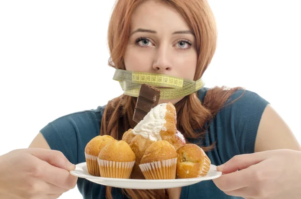 Mujer con un centímetro en la boca incapaz de comer todos los dulces y el azúcar, un montón de galletas en un plato. Dieta sin dulces —  Fotos de Stock