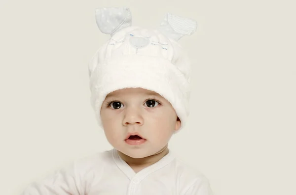 Onschuldige baby dragen een witte hoed op zoek schattig. Jongen gekleed voor winter, mooie pasgeborene. Schattige baby portret op zoek nieuwsgierig. Baby gekleed als een grappige bunny met een witte hoed met konijn oren — Stockfoto