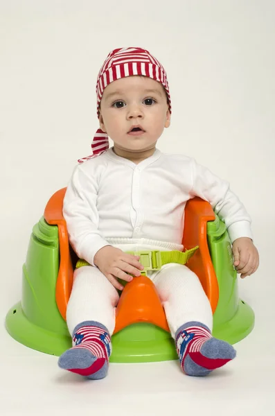 Schattige kleine jongen ontspannen in een speelgoed stoel klaar voor zijn diner. Baby kijken nieuwsgierig met grote ogen en mond open. Speelse jongen verkleed als een piraat — Stockfoto