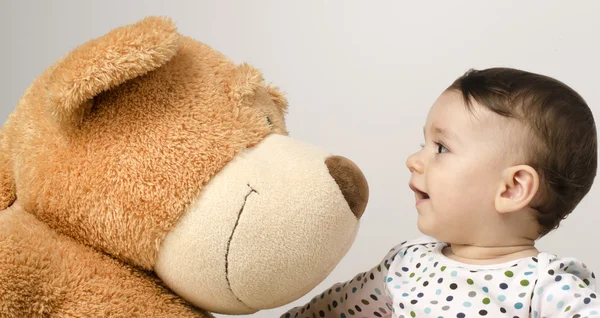 Beautiful innocent newborn speaking with his best friend, teddy bear. Adorable baby playing, having fun with his bear toy. Little sweet kid talking and listening his toy — Stock Photo, Image