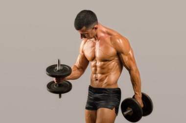 Güçlü vücut geliştirmeci adam mükemmel abs, omuzlar, pazı, triceps ve göğüs, ağır dumbbells ile eğitim, kollarını esneme kişisel fitness eğitmeni ile