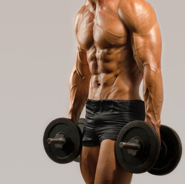 Güçlü vücut geliştirmeci adam mükemmel abs, omuzlar, pazı, triceps ve göğüs, ağır dumbbells ile eğitim, kollarını esneme kişisel fitness eğitmeni ile