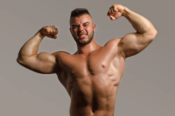 Kulturista nahoře bez, protahuje své velké bicepsy. Silný muž s perfektní abs, ramena, biceps, triceps a hrudníku — Stock fotografie