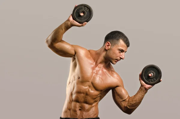 Stark bodybuilder man med perfekta abs, axlar, biceps, triceps och bröst, personlig tränare träning med tunga hantlar, böja armarna — Stockfoto