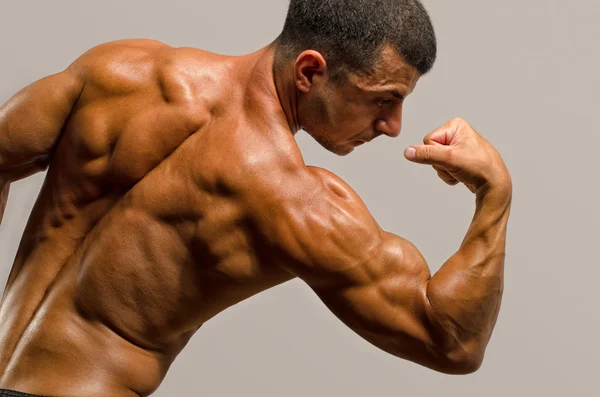 Culturista mostrando i muscoli della schiena, spalle, tricipiti e bicipiti, personal fitness trainer — Foto Stock