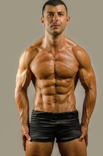 Forte fisiculturista com seis pack.Strong homem fisiculturista com abdominais perfeitos, ombros, bíceps, tríceps e peito, personal fitness trainer flexionando seus músculos — Fotografia de Stock