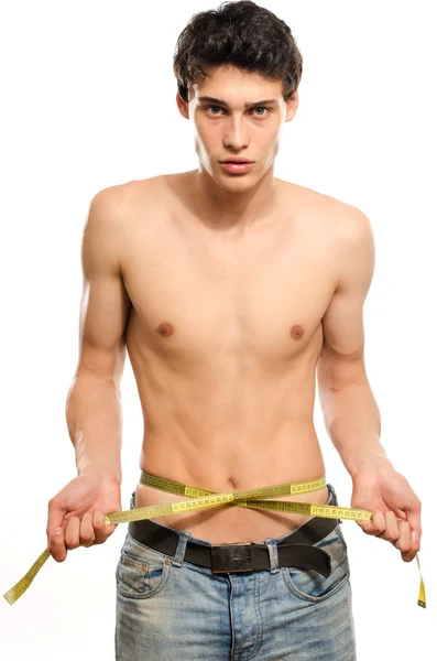 Skinny young man posing fashion with a centimeter, anorexic look. Slim body, young man keeping a strict diet and measuring himself — Stock Photo, Image