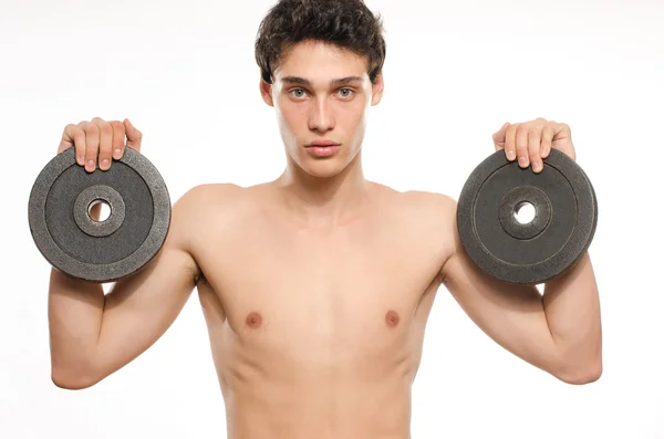 Der schlanke Mann trainiert seinen Bizepsmuskel. schöner Teenager, der zwei Hanteln hebt. Magersüchtiger junger Mann trainiert, um stärker zu werden — Stockfoto