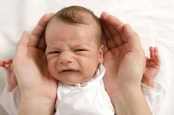 Beautiful innocent newborn crying looking at his father. Adorable little boy upset in father's protective hands.Dad holding his newborn with love. Stock Picture