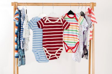 Dressing closet with clothes arranged on hangers.Colorful onesie of newborn,kids, toddlers, babies on a rack.Many colorful t-shirts, shirts,blouses, onesie hanging