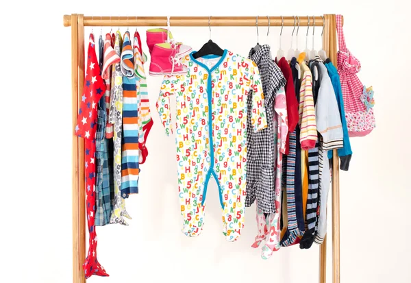 Dressing closet with clothes arranged on hangers.Colorful wardrobe of newborn,kids, toddlers, babies full of all clothes.Many t-shirts,pants, shirts,blouses,yellow hat,shoes, onesie hanging — Stock Photo, Image
