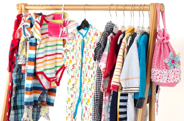 Dressing kast met kleren gerangschikt op hangers. Kleurrijke garderobe van pasgeboren kinderen, peuters, baby's vol met alle kleren. Vele t-shirts, broeken, shirts, blouses, gele hoed, schoenen, onesie opknoping — Stockfoto