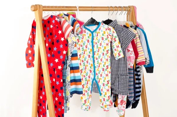 Garderoba szafa z ubrania na wieszakach. Kolorowe szafa noworodków, dzieci, niemowląt, dzieci pełne wszystkie ubrania. Wiele t shirty, spodnie, koszule, bluzki, żółty kapelusz, buty, onesie wiszące — Zdjęcie stockowe