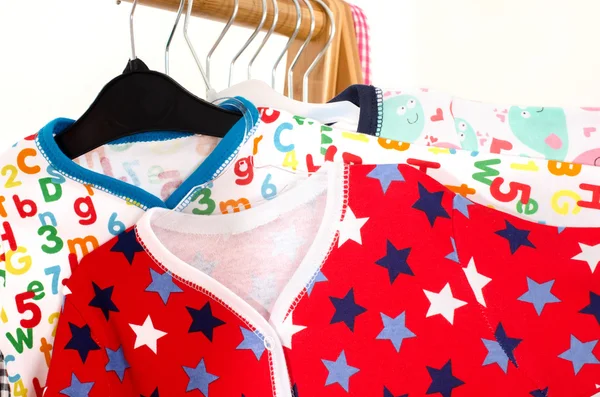 Lemari pakaian dengan pakaian diatur pada hangers.Colorful onesie dari bayi yang baru lahir, anak-anak, balita, bayi pada raket. Banyak warna-warni t-shirt, kemeja, blus, onesie menggantung — Stok Foto