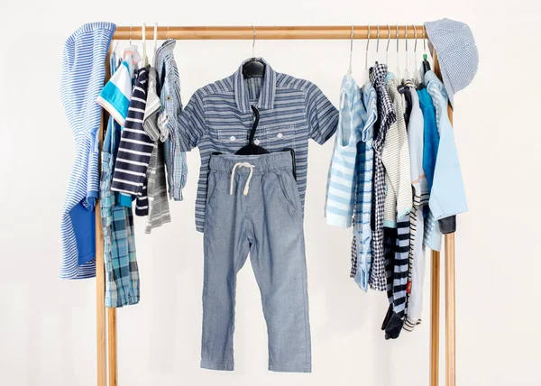 Kleiderschrank mit Kleidern auf Kleiderbügeln arrangiert.Blau-weißer Kleiderschrank von Neugeborenen, Kindern, Kleinkindern, Babys voller Kleidung. Viele T-Shirts, Hosen, Hemden, Blusen, blauer Hut, Onesie hängen — Stockfoto
