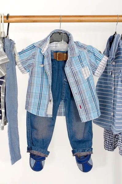 Dressing closet with clothes arranged on hangers.Blue and white wardrobe of newborn,kids, toddlers, babies full of all clothes.T-shirts,pants, shirts, hanging — 图库照片