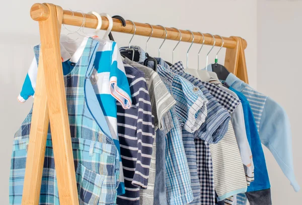 Armario de vestir con ropa arreglada en hangers.Blue y blanco armario de recién nacidos, niños, niños pequeños, bebés llenos de todas las clothes.Many camisetas, pantalones, camisas, blusas, onesie colgando — Foto de Stock