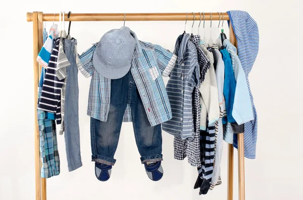 Soyunma dolap askı düzenlenmiş giysileri ile. Yeni doğmuş bebek, çocuk, küçük çocuklar, bebekler tüm giysiler tam mavi ve beyaz gardırop. Birçok t-gömlek, pantolon, gömlek, bluz, mavi şapka, asılı onesie