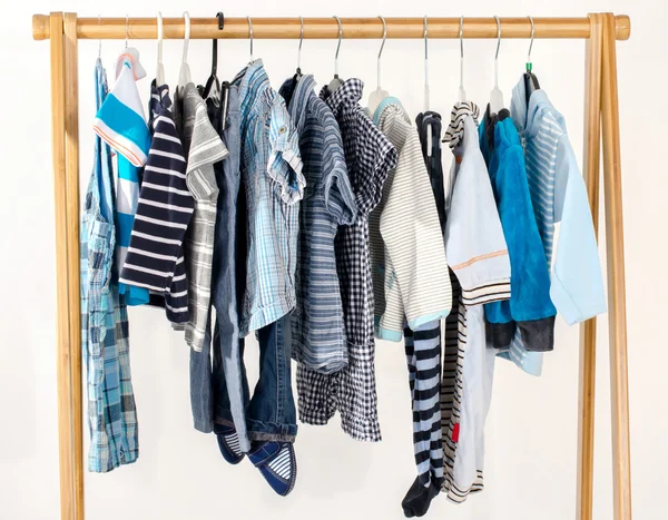 Dressing closet with clothes arranged on hangers.Blue and white wardrobe of newborn,kids, toddlers, babies full of all clothes.Many t-shirts,pants, shirts,blouses, onesie hanging — ストック写真