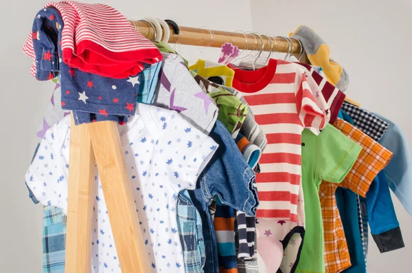 Kleiderschrank mit Kleidung auf Kleiderbügeln arrangiert.Bunte Garderobe von Neugeborenen, Kindern, Kleinkindern, Babys voller Kleidung. Viele T-Shirts, Hosen, Hemden, Blusen, Onesie hängen — Stockfoto