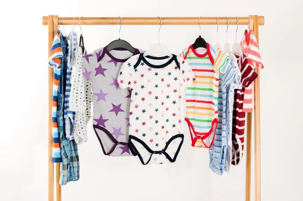 Lemari pakaian dengan pakaian diatur pada hangers.Colorful onesie dari bayi yang baru lahir, anak-anak, balita, bayi pada raket. Banyak warna-warni t-shirt, kemeja, blus, onesie menggantung — Stok Foto