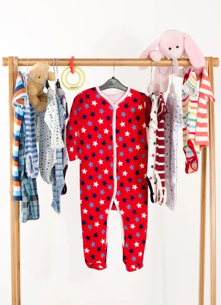 Dressing closet with clothes arranged on hangers.Colorful wardrobe of newborn,kids, toddlers, babies full of all clothes.Many t-shirts,pants, shirts,blouses, onesie hanging, bear and rabbit toy — Stock Photo, Image