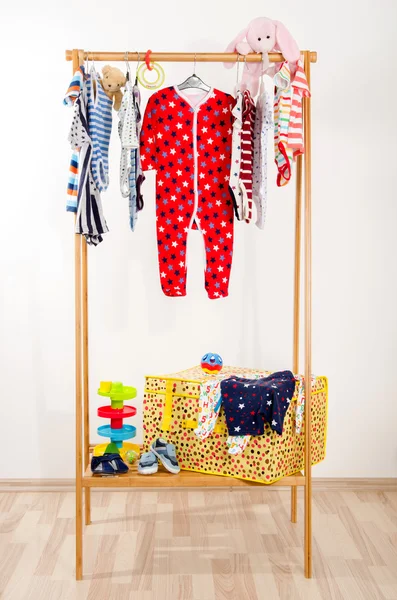 Dressing closet with clothes arranged on hangers.Colorful wardrobe of newborn,kids, toddlers, babies full of all clothes.Many t-shirts,pants, shirts,blouses, onesie hanging, rabbit and bear toy — Stock Photo, Image