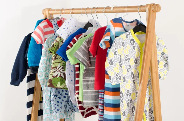 Dressing closet with clothes arranged on hangers.Colorful wardrobe of newborn,kids, toddlers, babies full of all clothes.Many t-shirts,pants, shirts,blouses, onesie hanging — Stock Photo, Image