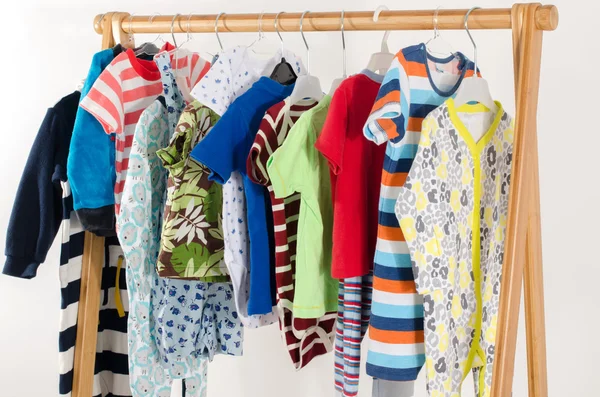 Kleiderschrank mit Kleidung auf Kleiderbügeln arrangiert.Bunte Garderobe von Neugeborenen, Kindern, Kleinkindern, Babys voller Kleidung. Viele T-Shirts, Hosen, Hemden, Blusen, Onesie hängen — Stockfoto