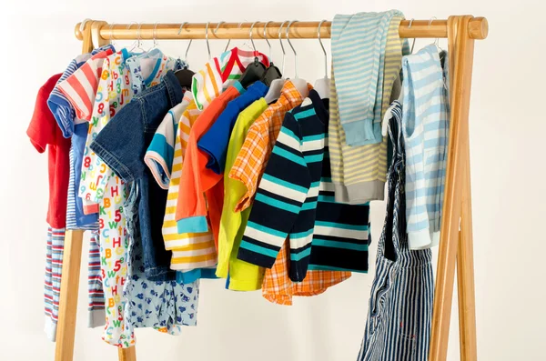 Armoire de dressing avec des vêtements disposés sur cintres. Armoire colorée de nouveau-né, enfants, tout-petits, bébés pleins de tous les vêtements. De nombreux t-shirts, pantalons, chemises, chemisiers, une pendaison — Photo