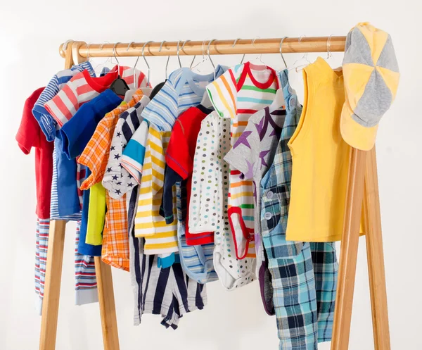 Dressing closet with clothes arranged on hangers.Colorful wardrobe of newborn,kids, toddlers, babies full of all clothes.Many t-shirts,pants, shirts,blouses,yellow hat, onesie hanging — Zdjęcie stockowe