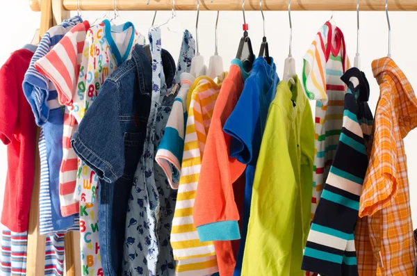 Dressing closet with clothes arranged on hangers.Colorful wardrobe of newborn,kids, toddlers, babies full of all clothes.Many t-shirts,pants, shirts,blouses, onesie hanging — Stock Photo, Image