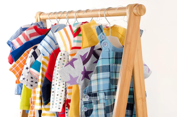 Kleiderschrank mit Kleidung auf Kleiderbügeln arrangiert.Bunte Garderobe von Neugeborenen, Kindern, Kleinkindern, Babys voller Kleidung. Viele T-Shirts, Hosen, Hemden, Blusen, Onesie hängen — Stockfoto