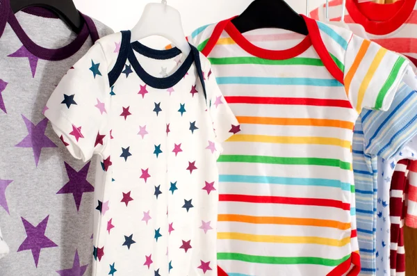 Vestidor armario con ropa arreglada en hangers.Colorful onesie de recién nacidos, niños, niños pequeños, bebés en un rack.Many coloridas camisetas, camisas, blusas, onesie colgando Fotos De Stock Sin Royalties Gratis