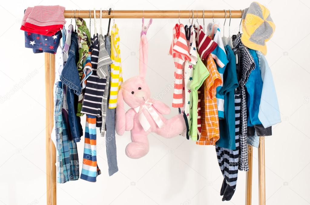 Dressing closet with clothes arranged on hangers.Colorful wardrobe of newborn,kids, toddlers, babies full of all clothes.Many t-shirts,pants, shirts,blouses, onesie on a rack, pink rabbit toy hanging