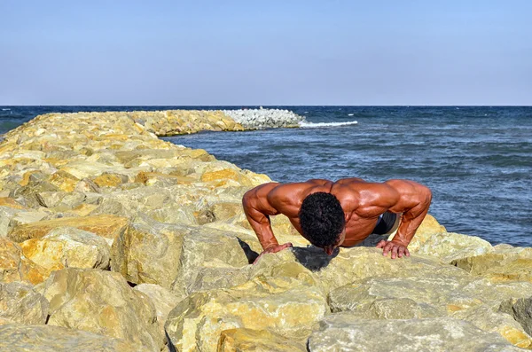Strong bodybuilder with six pack.Fitness trainer with perfect abs, shoulders,biceps, triceps,chest, flexing his muscles on the beach, training in vacation, doing push ups in the sand — Φωτογραφία Αρχείου