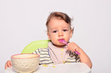 Baby eating food with a spoon, toddler eating messy and getting