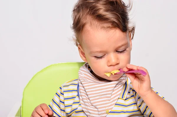 Bebê comendo comida com uma colher, criança comendo bagunçado e ficando — Fotografia de Stock