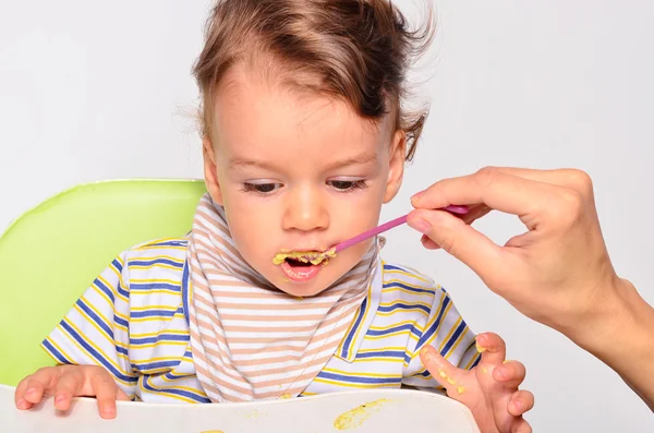 Baby eating food with a spoon, toddler eating messy and getting — Stockfoto