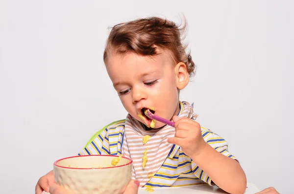 Baby eating food with a spoon, toddler eating messy and getting